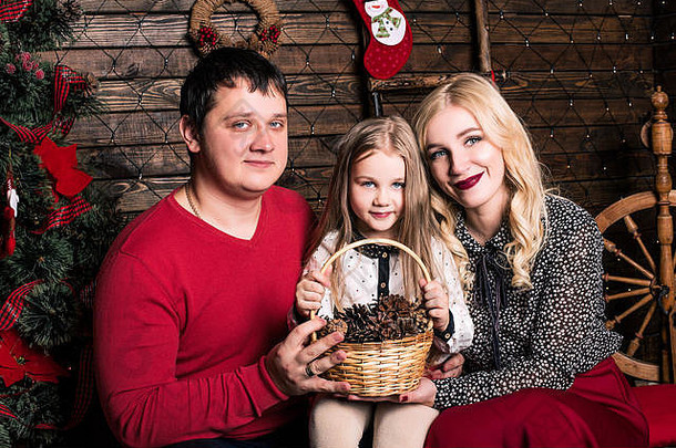一个穿着红色衣服的美丽的年轻家庭正在一起欢度圣诞节，他们坐在客厅的地板上，旁边是一棵装饰精美的圣诞树sm