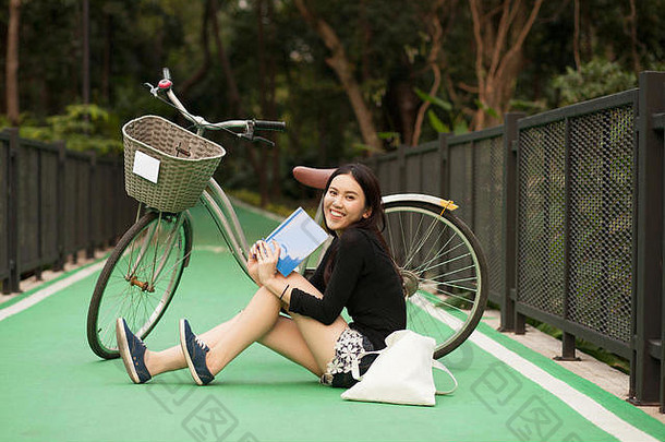 漂亮的<strong>泰国</strong>女孩阅读书坐着自行车公园