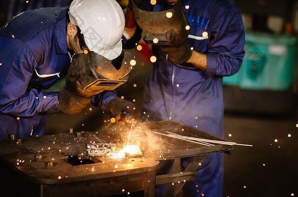 工业工人在金属工厂用tig焊接钢和保护视力的安全面罩。