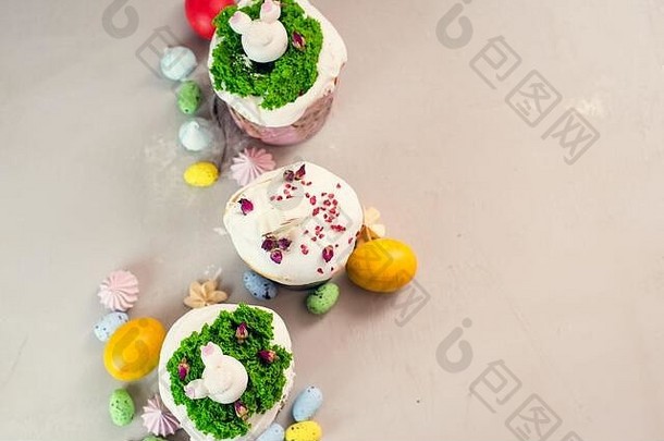 正统的复活节蛋糕用奶油装饰，形状为草和兔子雕像，白色巧克力制成，背景为灰色，旁边是彩蛋。复活节食品的概念。这是给孩子们的主意。