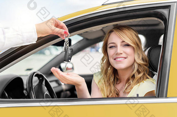 一个漂亮的女人在车里拿到车钥匙。租赁或购买汽车。