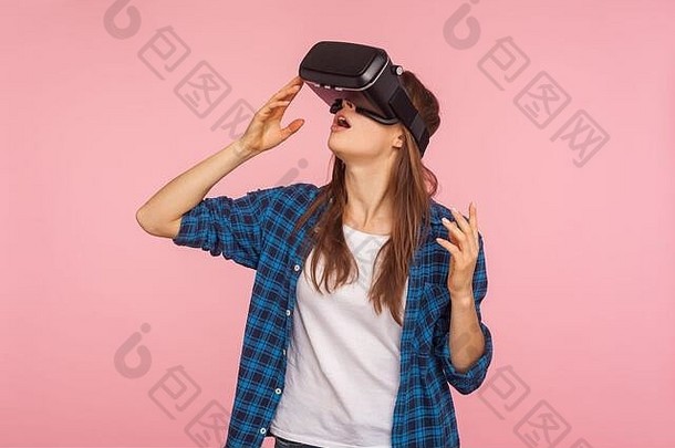 穿着格子衬衫、戴着虚拟现实耳机、脸上带着惊奇表情玩虚拟现实游戏、对创新技术感到惊讶的游戏玩家女孩的肖像