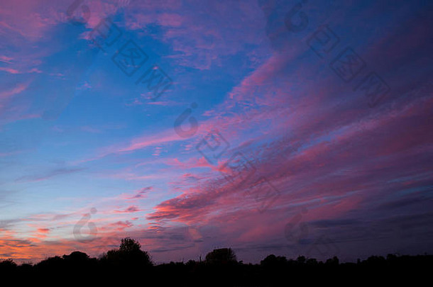在英国弗雷明翰萨福克郡看到的秋天傍晚日落，伴随着稀疏的粉红色和金橙色的高海拔卷<strong>云</strong>