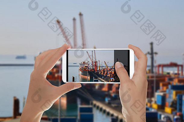 一名游客正在拍摄意大利集装箱码头的照片，起重机正在装载一艘大型货船。进出口物流