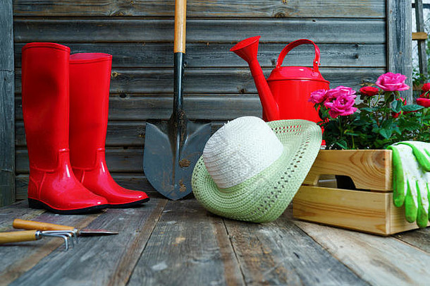 铲子、水壶、帽子、橡胶靴、一盒花、手套和园艺工具