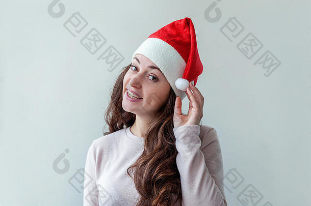 戴着红色圣诞老人帽、留着长发的美丽女孩，被隔离在白色背景上，看上去快乐而兴奋。年轻女子肖像，真实情感。圣诞快乐，新年快乐