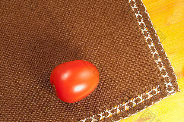 木桌上放着漂亮的西红柿和棕色的餐巾