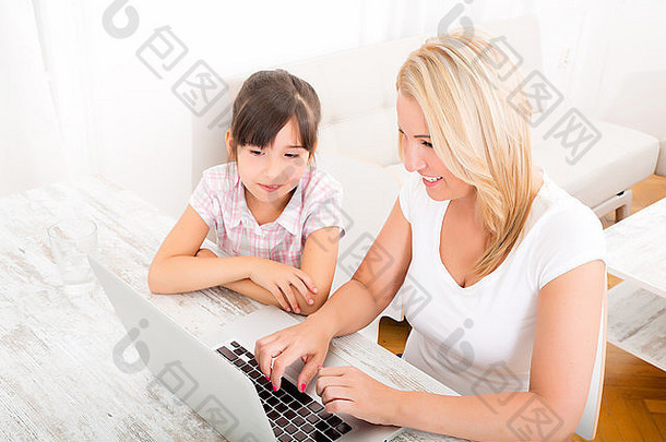 一位母亲和女儿在家看笔记本电脑。