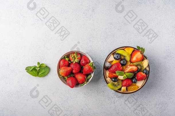 新鲜水果沙拉，不同的配料和薄荷色背景。健康饮食。空间。俯视图