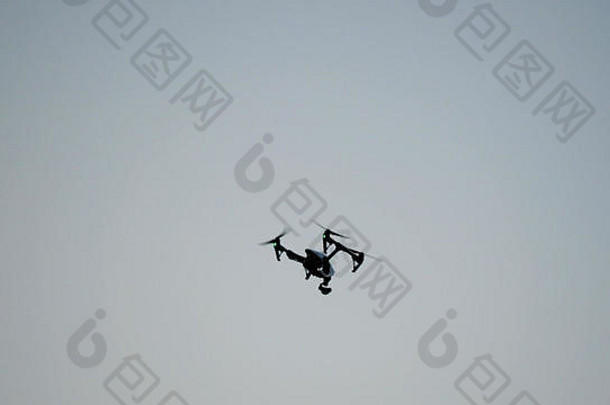 带摄像头的黑色无人机四架直升机飞越蓝天。天空中的黑色无人机。在空中飞行的四翼无人机，带有用于视频和照片制作的数码相机