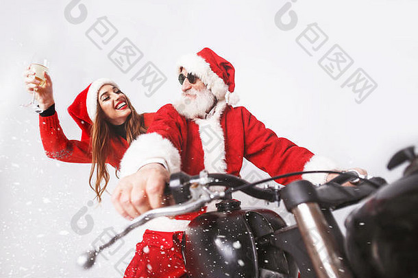 圣诞老人老人白色胡子穿sungasses年轻的夫人老人穿圣诞老人他红色的毛衣太阳镜骑摩托车下雪夫人老人笑香槟一年圣诞节假期记忆礼物购物折扣商店雪少女圣诞老人老人化妆发型狂欢节
