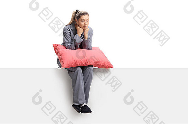 悲伤的年轻女子，枕着枕头，坐在白色背景上的一块嵌板上