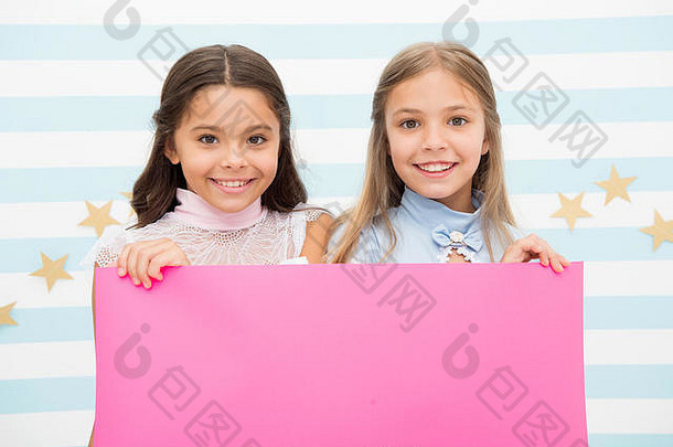 孩子们的学校公告。你的广告在这里。小女孩和孩子们拿着粉红色的纸准备学校公告。空间的粉色背景