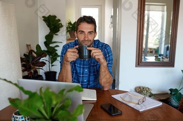 微笑年轻的男人。喝咖啡工作首页