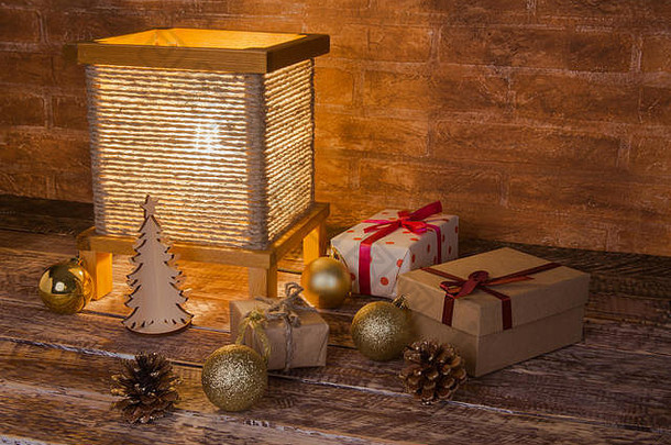 木制背景上的复古台灯、礼品盒和彩色圣诞球。假期到了。
