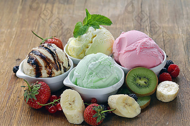 木桌上摆放着草莓、香蕉、薄荷、巧克力和新鲜浆果等各式<strong>冰淇淋</strong>