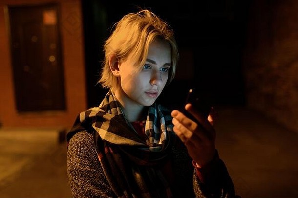 晚上在街上使用智能<strong>手机</strong>的年轻女子。