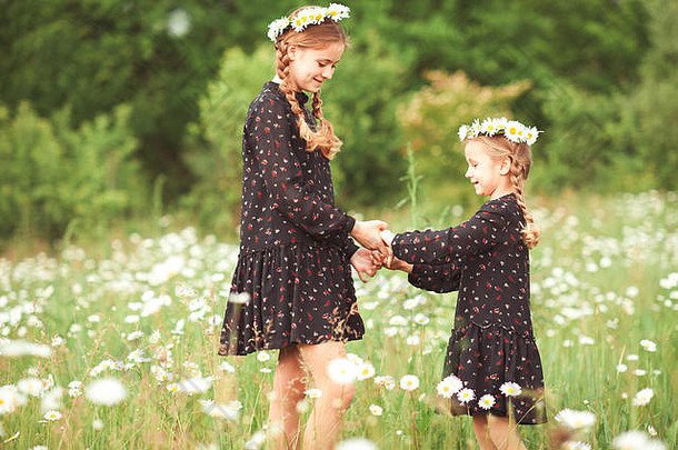 微笑女孩姐妹玩Chamomiles草地在户外夏天时间童年