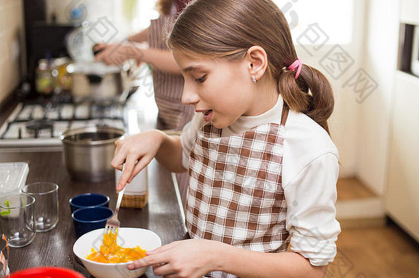小十几岁的女孩围裙搅拌鸡蛋白色碗厨房