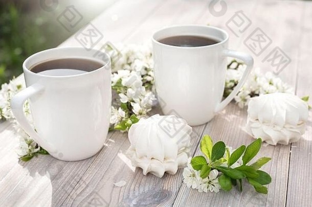 美丽的瓷咖啡杯棉花糖甜点装饰白色樱桃花木表格春天花园设置太阳光