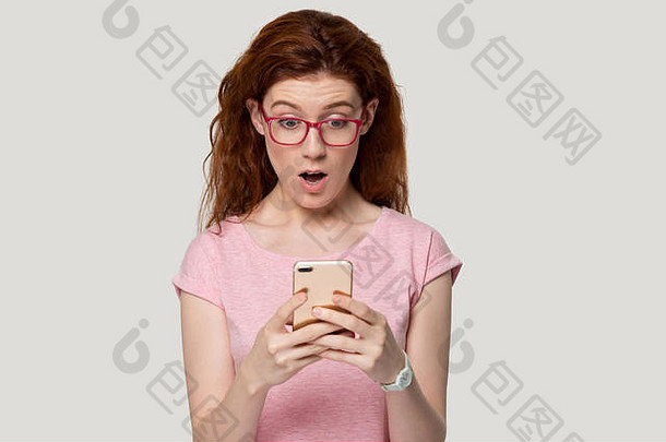 惊讶红色头发的人女孩持有手机意想不到的消息