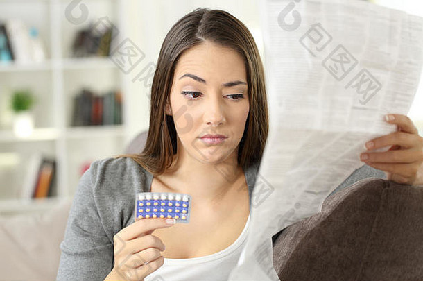 可疑的女人阅读传单采取避孕<strong>药</strong>片坐着沙发上生活房间房子室内