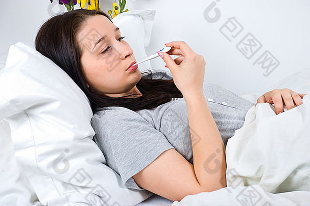 生病的年轻的女人冷检查温度床上