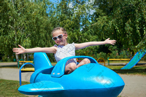 孩子女孩飞蓝色的飞机吸引力城市公园快乐童年夏天假期概念