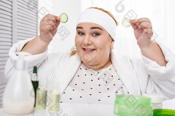 很高兴脂肪女人使黄瓜面具