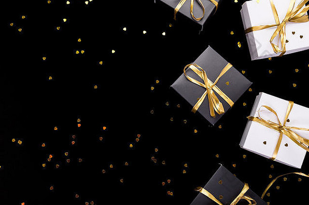 黑色的白色礼物盒子黄金丝带发光背景平躺复制空间