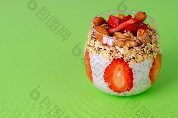 酸奶传讲布丁新鲜的草莓在一夜之间燕麦坚果玻璃绿色背景前面视图平衡健康的早餐概念
