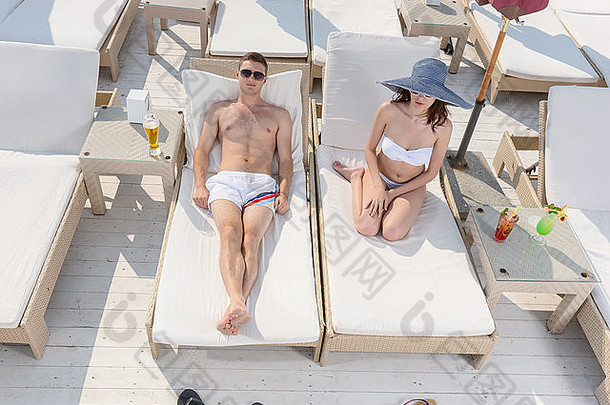年轻的夫妇享受懒惰的一天阳光放松躺著的人椅子海边度假胜地热带地区夏天假期