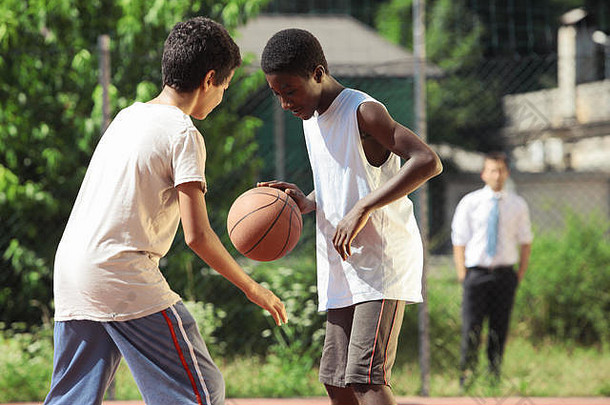 年轻的非洲男孩玩篮球在户外
