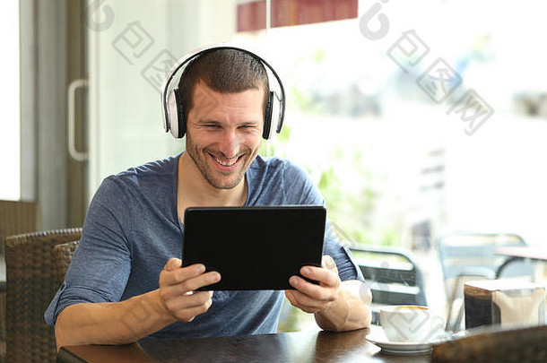 快乐男人。耳机平板电脑坐着咖啡商店
