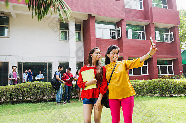 年轻的大学女孩学生朋友采取自拍照片聪明的电话大学校园
