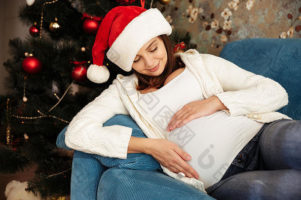 可爱的年轻的怀孕了女人<strong>圣诞</strong>节他说谎沙发上触碰肚子首页
