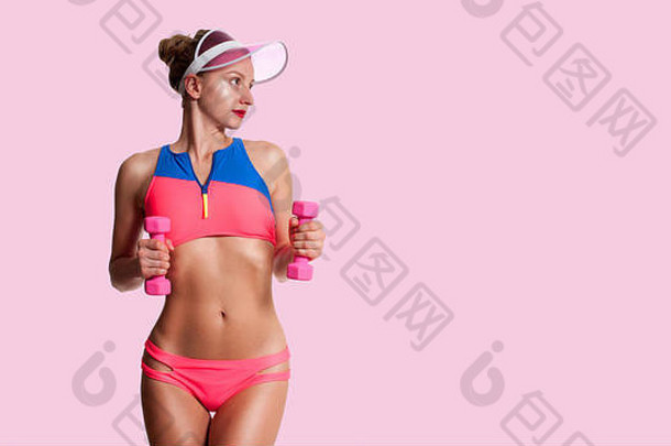 健身锻炼美丽的女人完美的运动身体持有哑铃粉红色的背景
