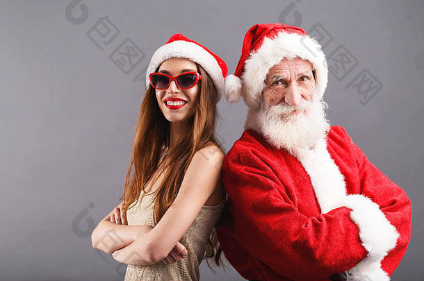 圣诞老人老人年轻的夫人老人穿圣诞老人他太阳镜站微笑灰色的背景一年圣诞节假期记忆礼物购物折扣商店雪少女圣诞老人老人化妆发型狂欢节