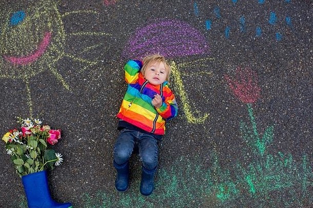 可爱的蹒跚学步的玩雨用粉笔写画沥青有趣的