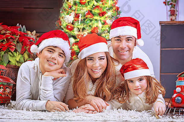 快乐家庭圣诞节夏娃快乐的父母可爱的孩子们说谎地板上美丽的装饰圣诞节树