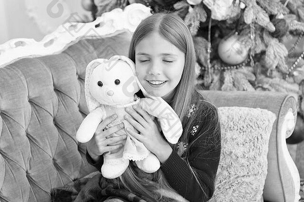 最可爱的玩具小女孩拥抱兔子玩具圣诞节玩具女孩可爱的兔子圣诞节树孩子玩软玩具小孩子快乐微笑现在