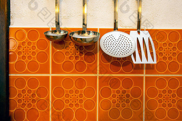 复古的厨房工具挂起古董橙色平铺的墙背景