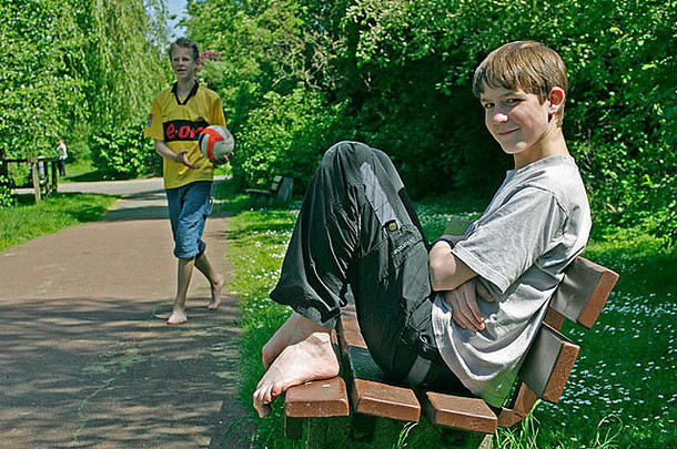 肖像十几岁的男孩坐着板凳上公园