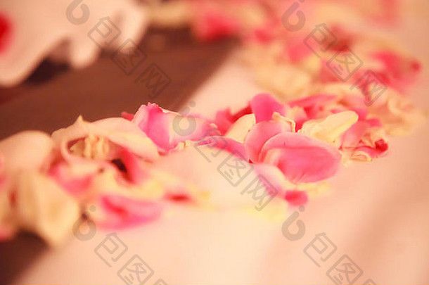 浪漫的酒店卧室室内装饰新鲜的粉红色的白色玫瑰花花瓣撒床上新婚夫妇婚礼周年纪念日honeym
