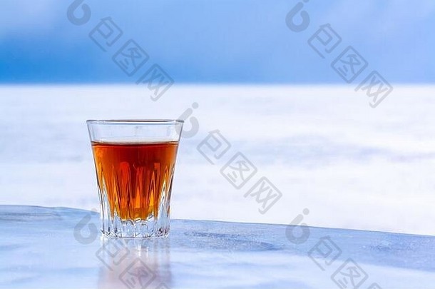 冷冻威士忌玻璃站冰背景模糊的雪天空橙色含酒精的喝玻璃复制空间一边视图