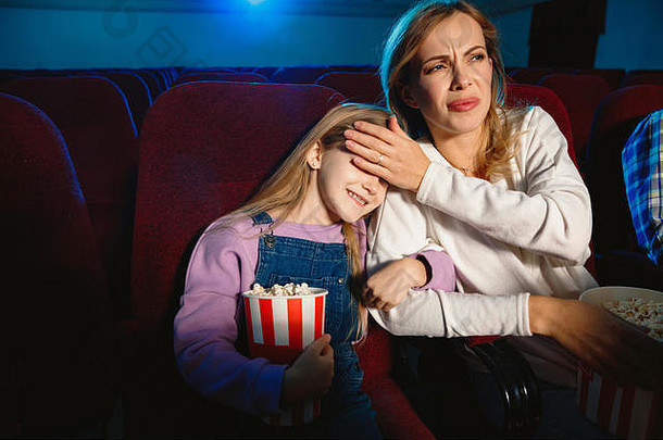 高加索人妈妈。女儿看电影电影剧院房子电影富有表现力的惊讶情感坐着有趣的关系爱家庭童年周末