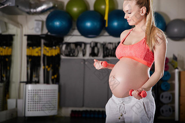 一边肖像怀孕了女人提升权重健身房