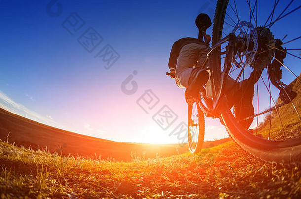 低角视图骑自行车的人站山自行车小道日落
