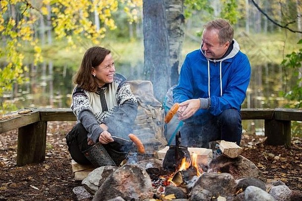 男人。女人烤篝火森林海岸湖使火烧烤快乐夫妇探索芬兰斯堪的那维亚景观
