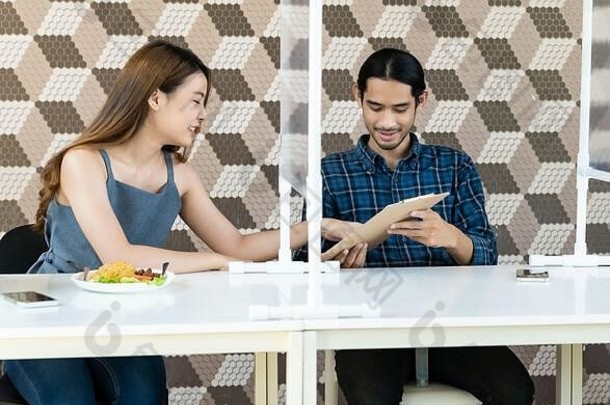 亚洲年轻的夫妇吃正常的社会距离餐厅表格盾分区减少感染冠状病毒科维德